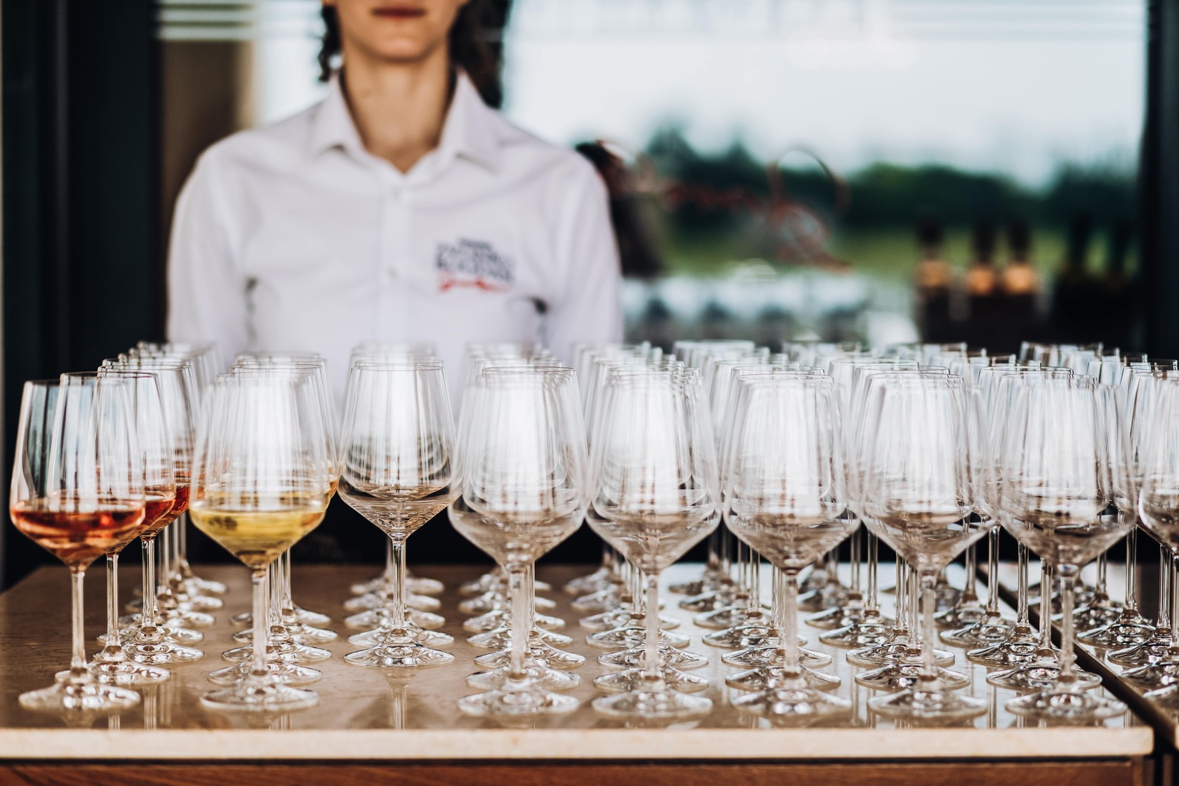 Une serveuse devant les verres de vin pour une prestation traiteur d'un événement professionnel avec l'agence Kap West Events.
