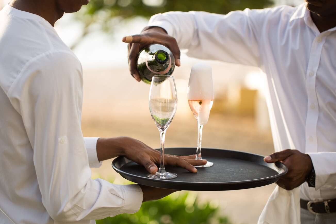 Des serveurs entrain de servir des coupes de champagnes lors d'une prestation traiteur d'un événement professionnel avec l'agence Kap West Events.